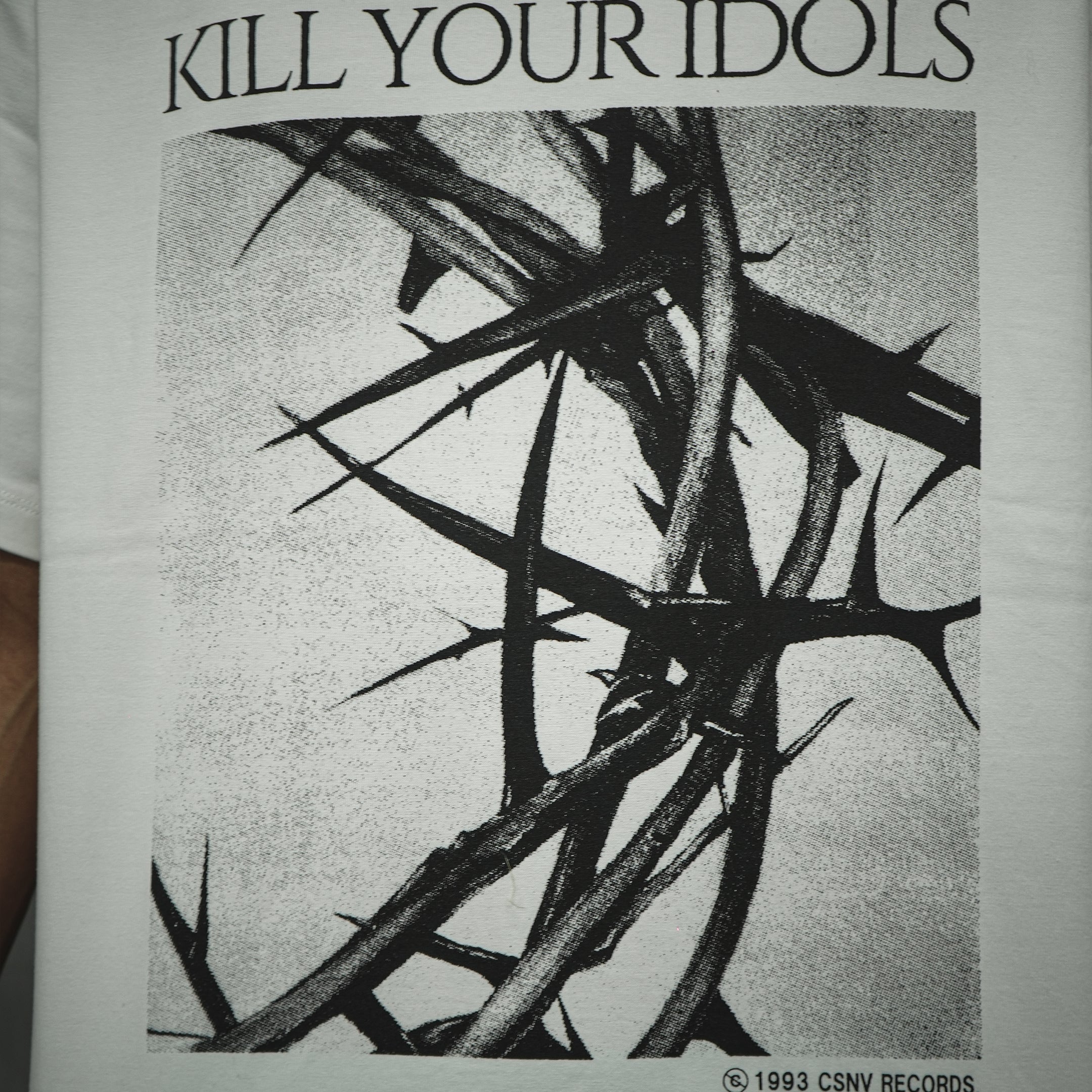 メゾンカサノバ 白のグラフィックTシャツ。フロントに「KILL YOUR IDOLS」のタイポグラフィと、退廃的なイバラのモノクロイラストをプリント。左裾に赤いブランドラベル付き。