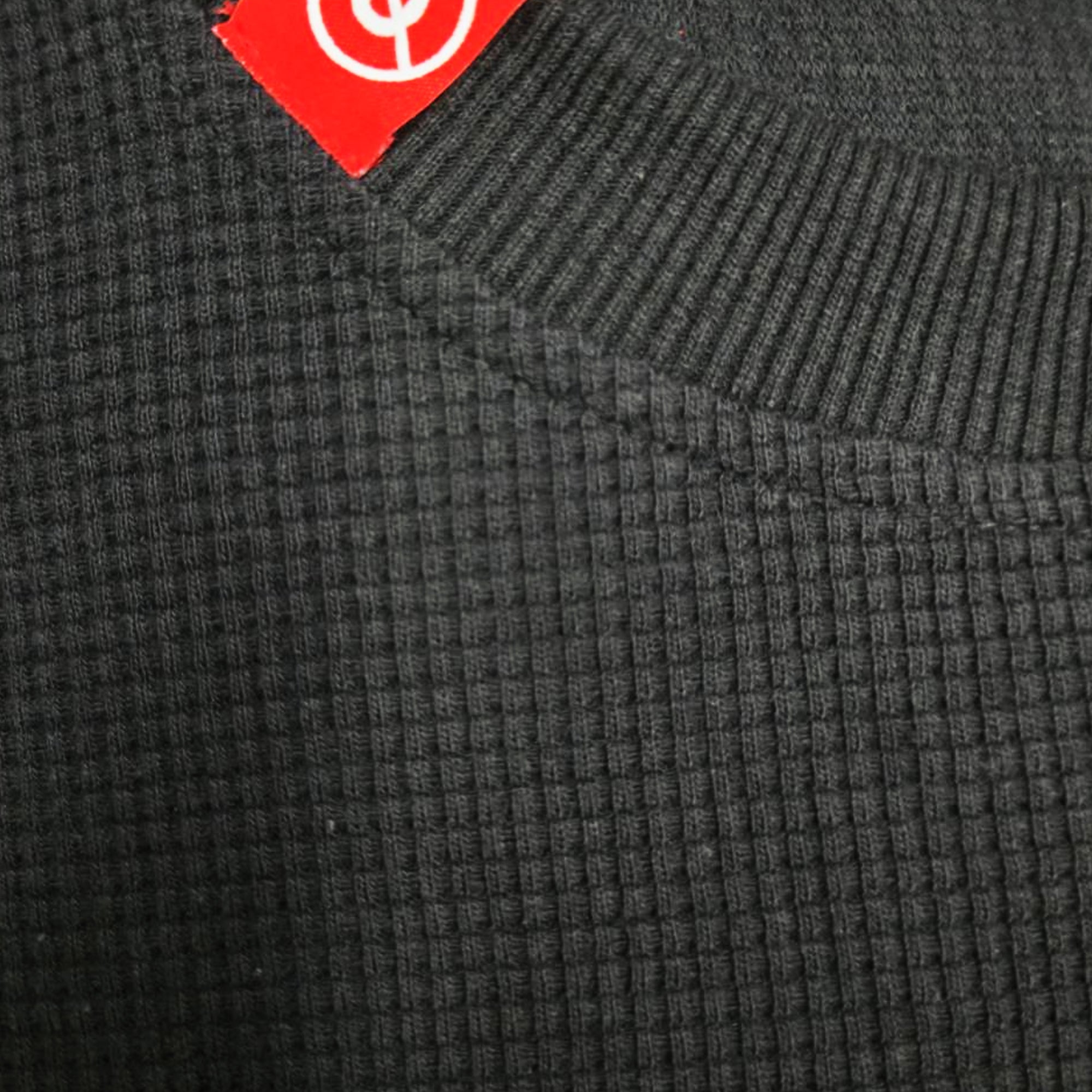 メゾンカサノバ 黒のワッフル編みクロップド長袖Tシャツ。裾は切りっぱなしのカットオフ仕様。首元の右側と左袖口に赤いブランドラベル付き。