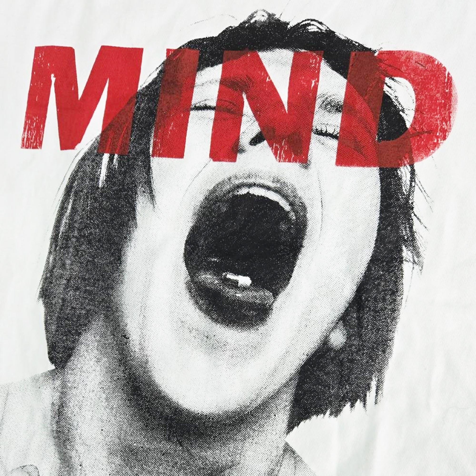 叫び声を上げる人物のモノクロシルクスクリーンプリントに、赤いステンシル調で「MIND」とプリントされた白いTシャツの背面の画像。Tシャツの袖には、黒い「MAISON CASANOVA」の織りネーム