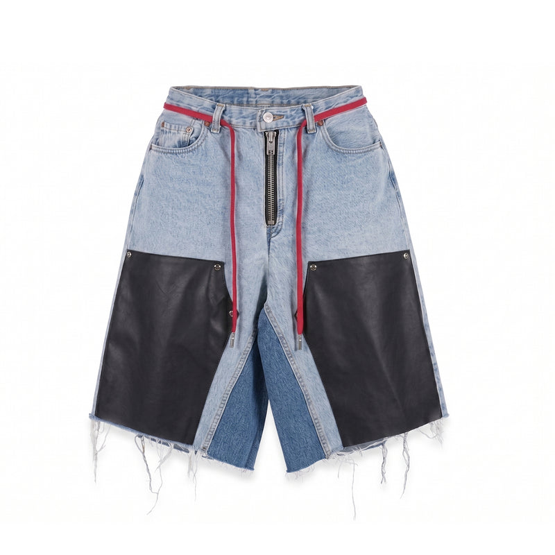 MAISON CASANOVAのライトブルーのデニムショーツ。フロントの中央には太いシルバージップがむき出しになっており、ウエストから赤い長い紐（ドローストリング）が垂れている。両脚の前部分には大きな黒いレザーのパッチがスタッズのような金具で留められている。内股部分は濃いブルーデニムで切り替えられ、裾は激しくほつれた切りっぱなしのダメージ加工が施されている。