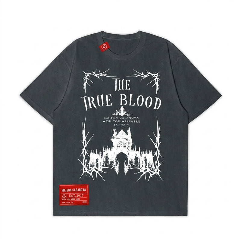 Maison Casanovaのヴィンテージ風ダークグレーTシャツ。フロントに「THE TRUE BLOOD」の白い文字と、茨に囲まれたゴシック様式の城のグラフィックプリント。首元と左裾に赤いブランドラベル付き。