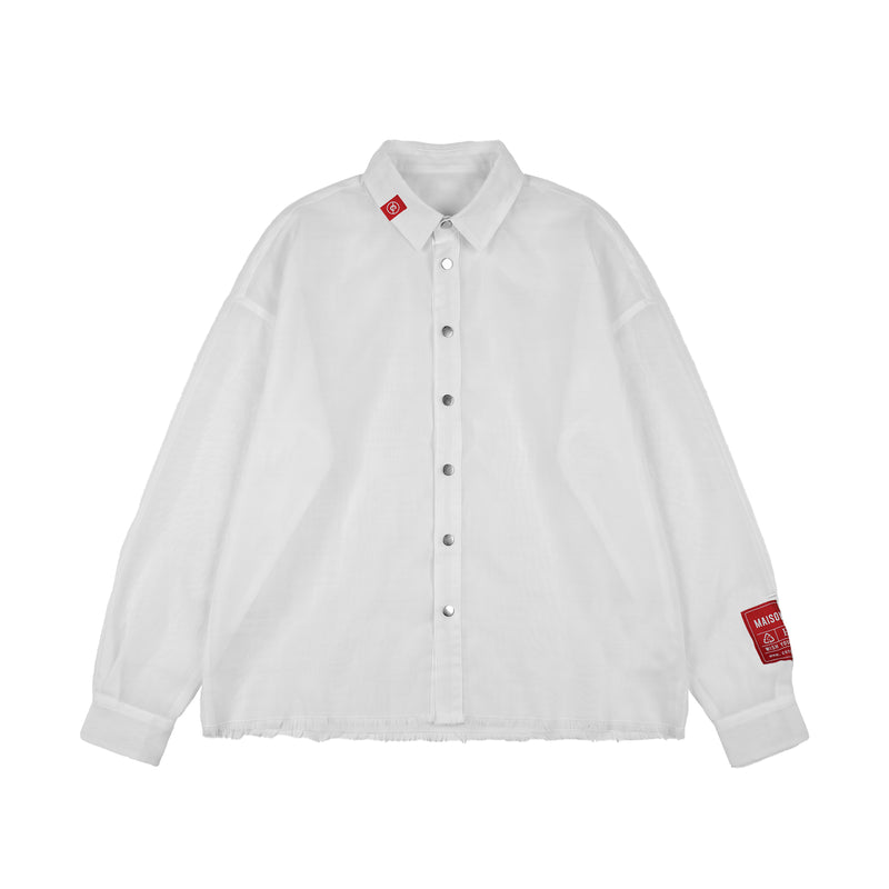MAISON CASANOVAの白い長袖シャツ。透け感のある軽やかなシアー素材を使用し、フロントにはシルバーのスナップボタンが並んでいる。裾は糸がほつれた切りっぱなしのデザイン。右側の襟に小さな赤いタグ、左袖の袖口付近には赤い長方形のブランドパッチが縫い付けられている。