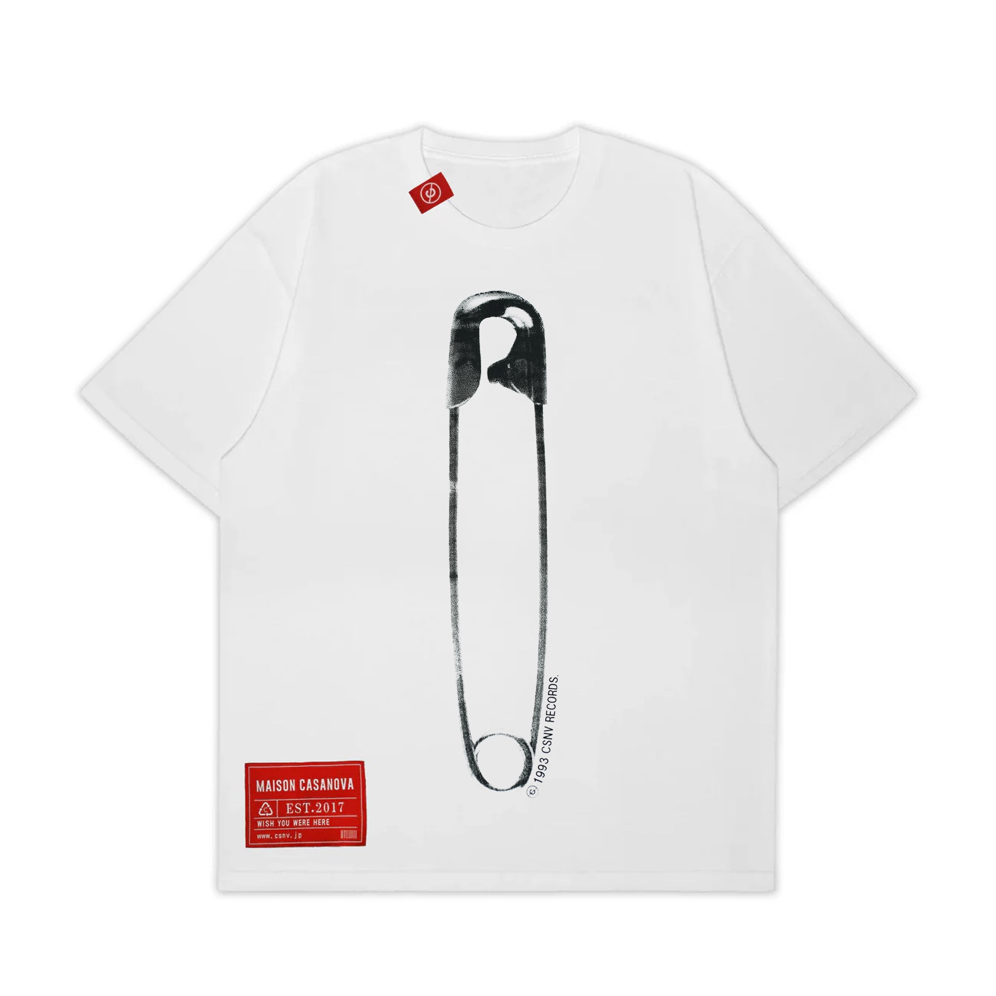 MAISON CASANOVAの白い半袖Tシャツ。フロント中央に、巨大な安全ピンのモノクログラフィック（ざらつきのあるハーフトーン調）が縦に大きくプリントされている。安全ピンの右下に沿うように「© 1993 CSNV RECORDS」の小さな文字。左下には赤い長方形のブランドパッチ。